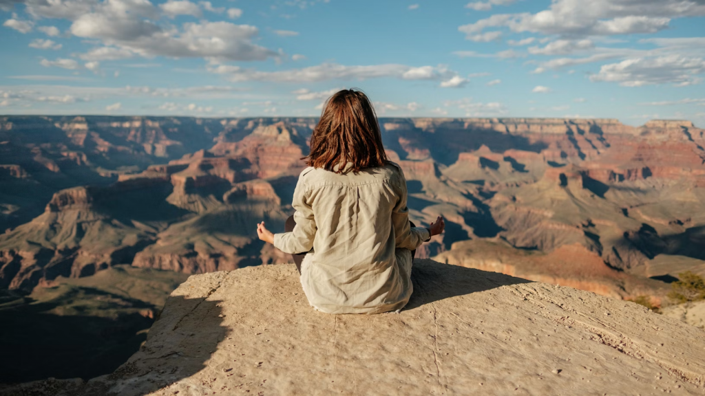 A woman meditates on a cliff.